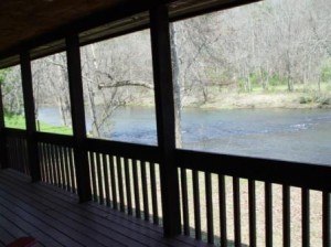 view of stream from covered wooden porch