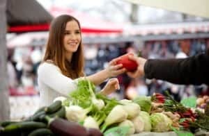 Farmer handing woman a red pepper at the Farmers Market.