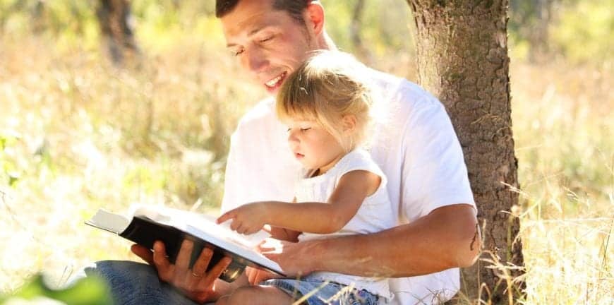 Father and daughter reading Bible in the park