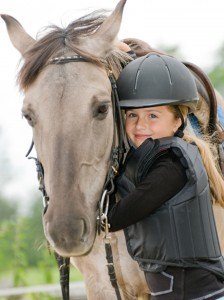 Little girl dressed as a jockey riding a horse