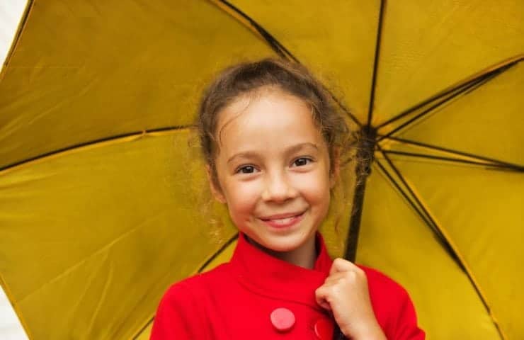 Little girl smiling with an umbrella on a rainy day