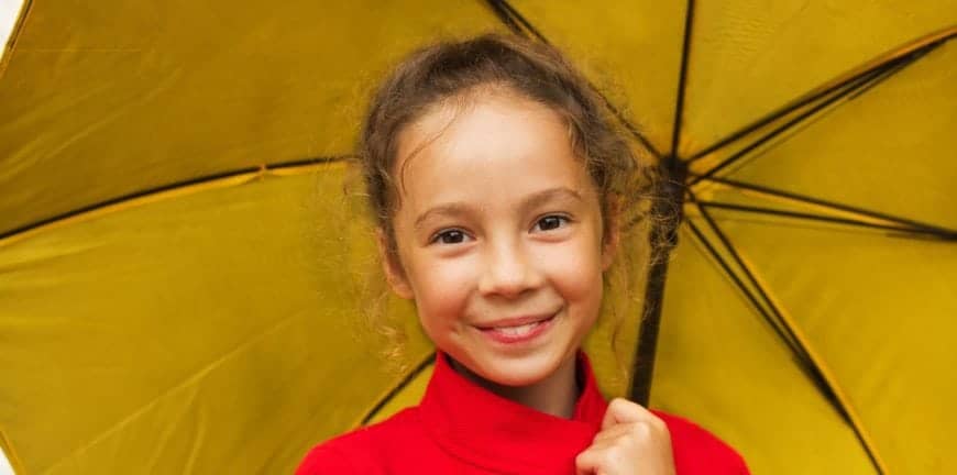 Little girl smiling with an umbrella on a rainy day