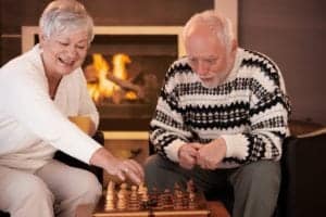 Older couple playing chess in front of the fireplace