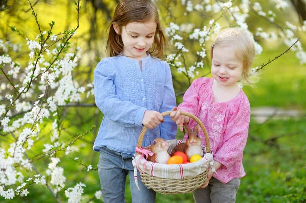 Young sisters holding an Easter basket near their cabin rental in the mountains of North Carolina