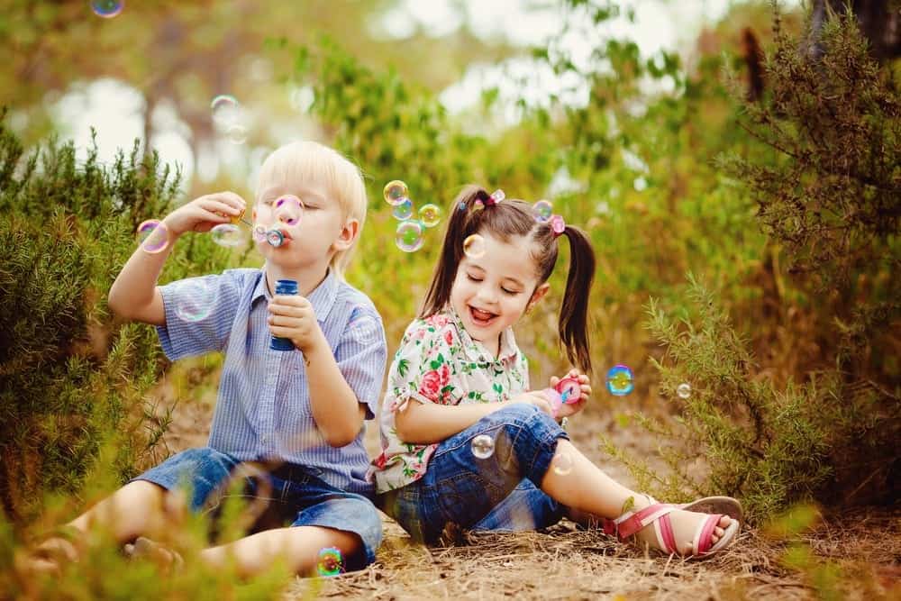 Young boy and girl having fun blowing bubbles outside of their 2 bedroom North Carolina cabin rental.