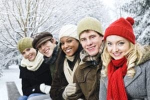 A group of friends sitting on a bench during the winter.