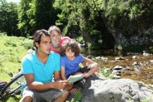 A family looking at a map beside a mountain river.