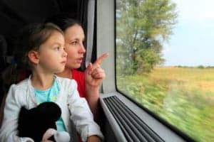 Mother and daughter looking out the window of a train.