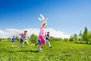 Kids playing with a toy airplane in a field.