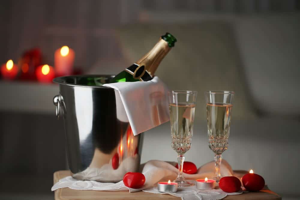 champagne in a tub next to glasses and candles