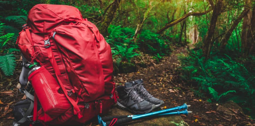 Red backpack, hiking shoes and hiking poles sitting on a trail in the Smoky Mountains