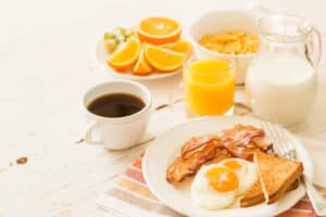 breakfast foods like eggs, toast, bacon, coffee, oranges, and milk